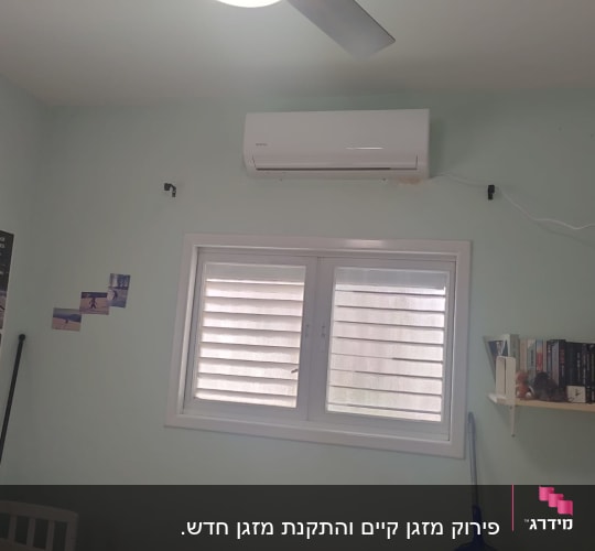 מזגן מותקן על קיר מעל חלון עם תריסים